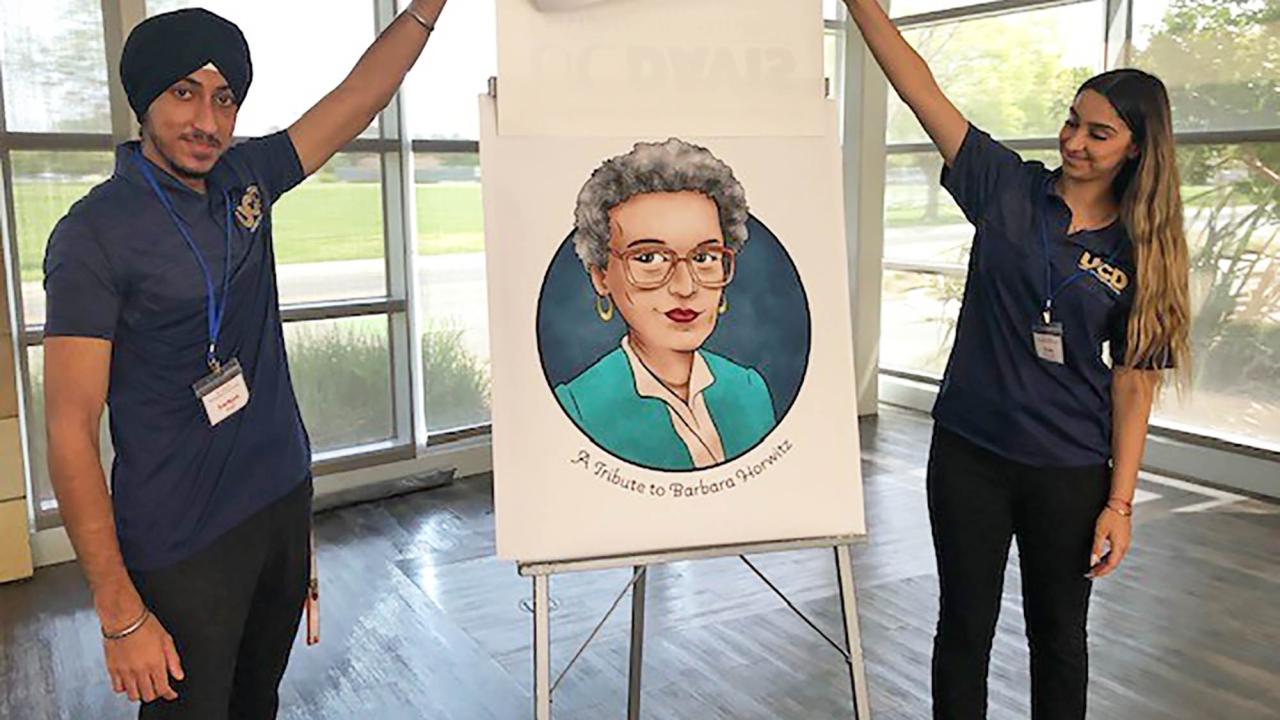 Two students unveiling a caricature of Barbara Horwitz