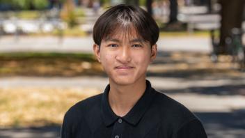 A person in a dark blue polo shirt standing outside