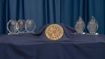 An assortment of trophies and medals on a blue cloth.
