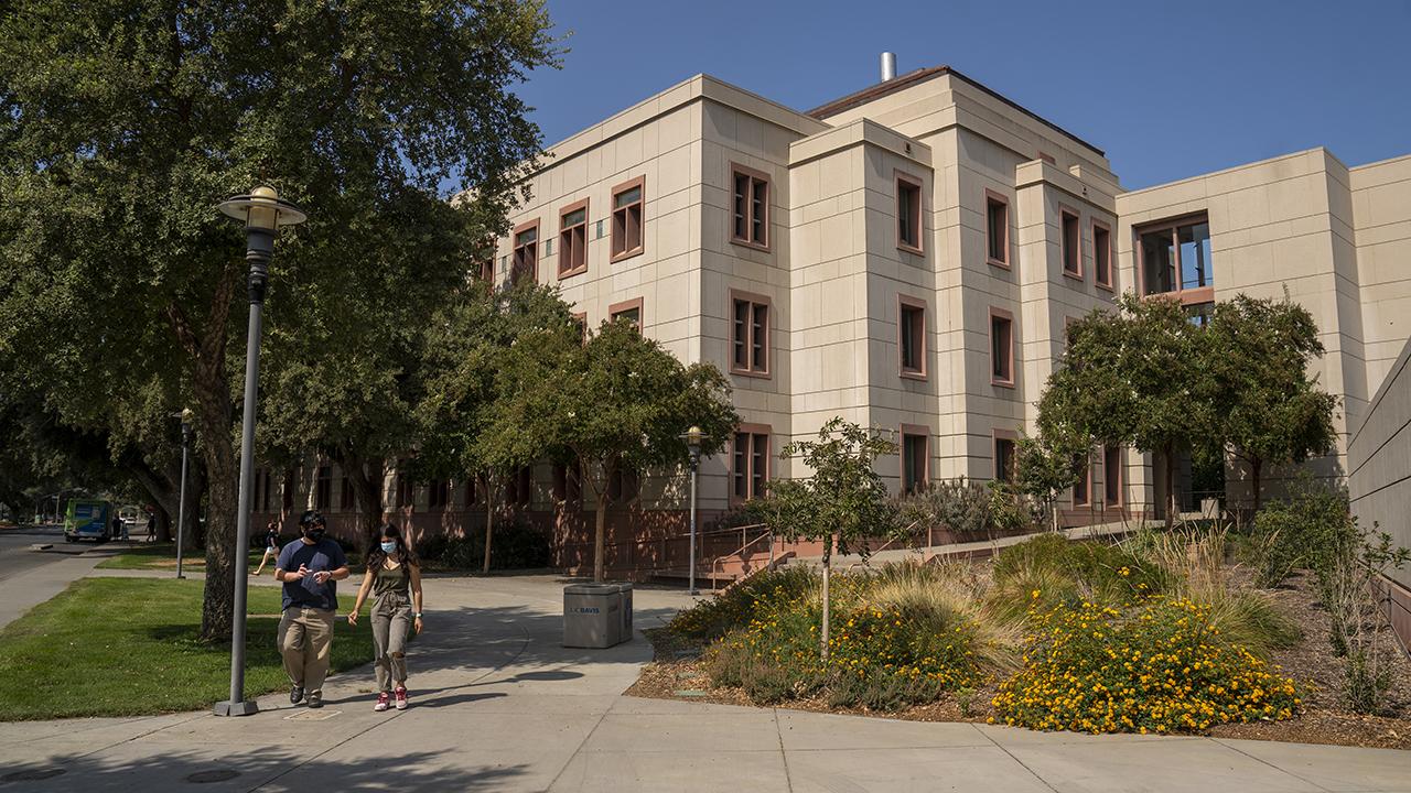 Photo of Green Hall and two masked students walking
