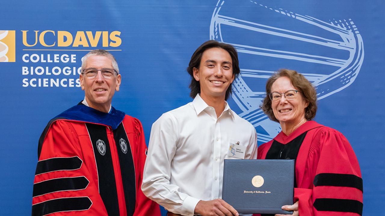 Dean Winey, male student, and Associate Dean Igo standing in front of a blue banner.
