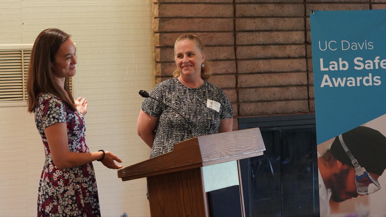 Two women standing near a podium with microphone